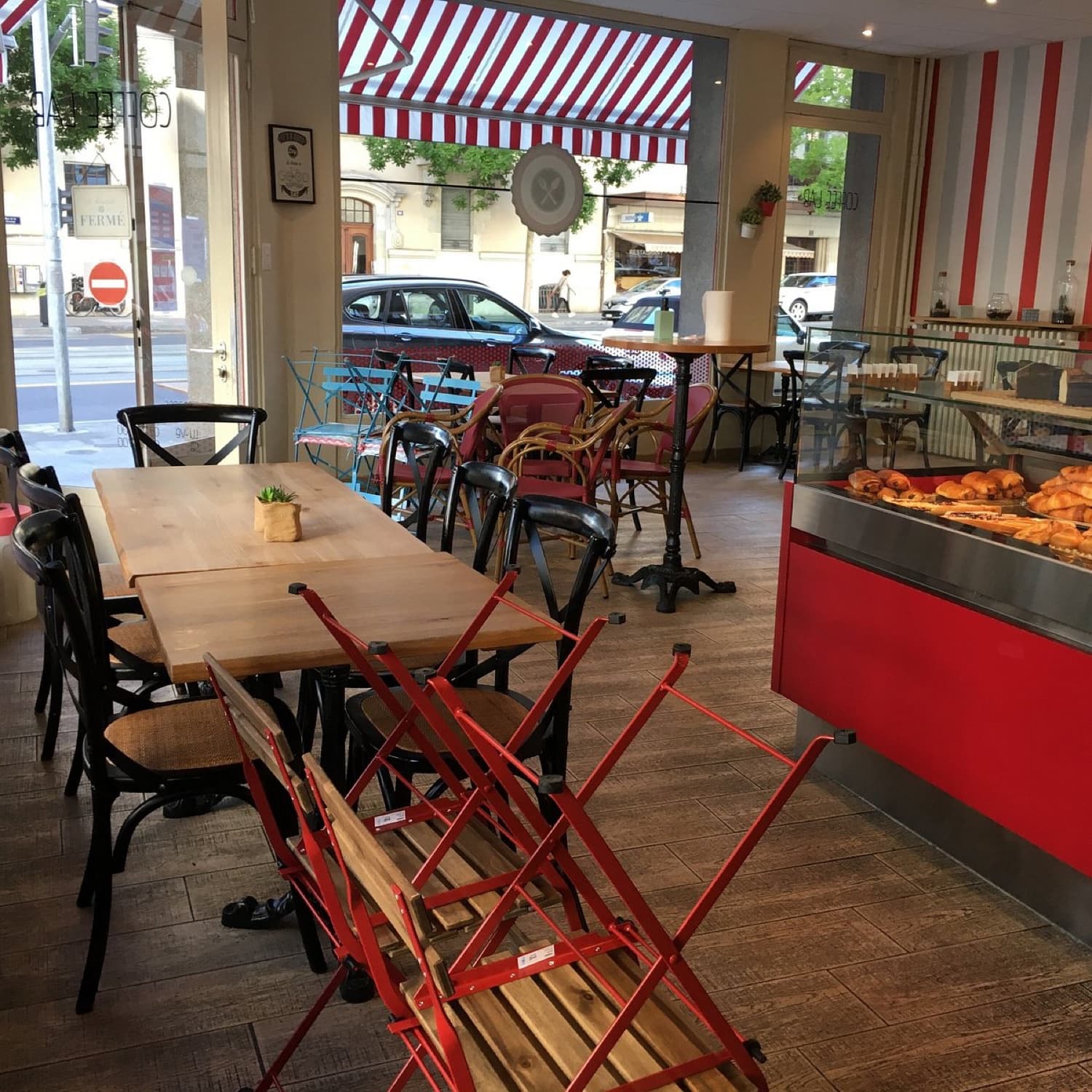 Intérieur du Coffee Lab, rue de la Servette : enseigne, comptoir à viennoiseries, tables bistrot et terrasse.
